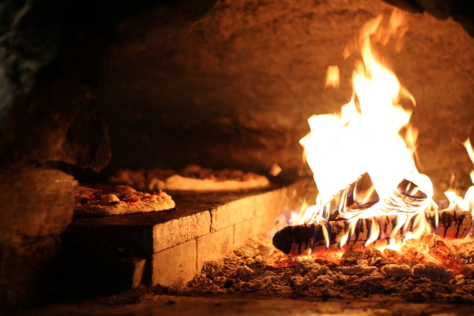 Versgebakken pizza uit traditionele houtoven.